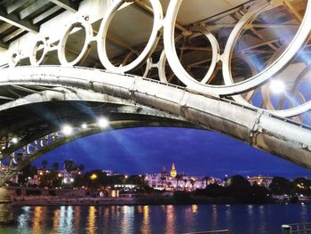 Illuminated bridge over river in city at night