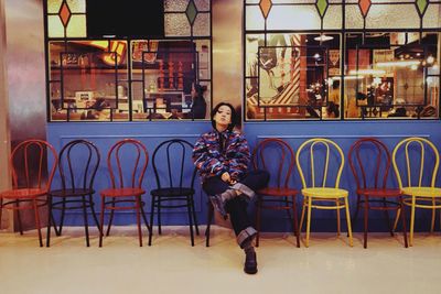 Full length portrait of woman sitting on chair at cafe