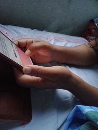 Midsection of woman using mobile phone on bed