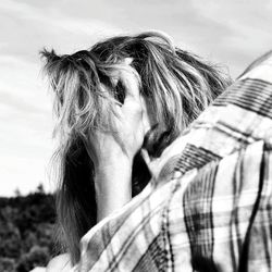 Cropped image of woman with hand in hair against sky