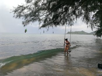 Rear view of people in sea against sky