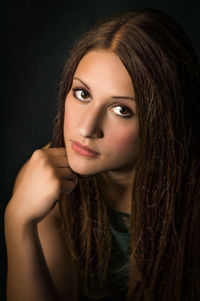 Close-up portrait of a beautiful young woman over black background