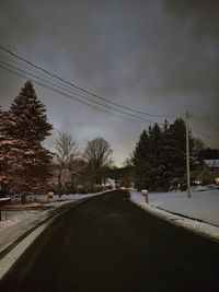 Road amidst trees against sky during winter