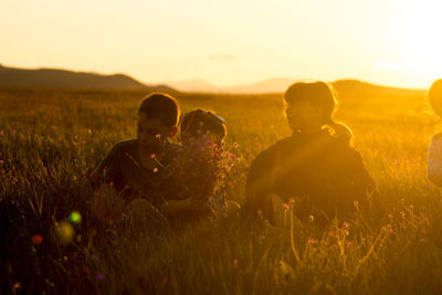 People sitting on field during sunset