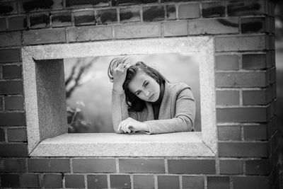 Portrait of young woman against brick wall