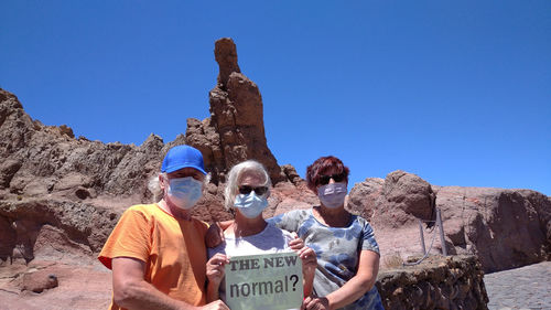 Portrait of people on rock against clear blue sky