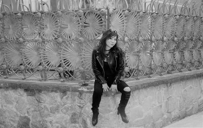 Full length portrait of young woman standing against wall