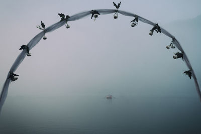 Low angle view of chain hanging over sea against sky