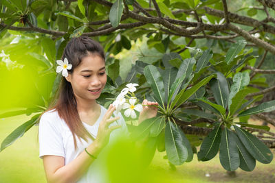 Smiling young woman against plants