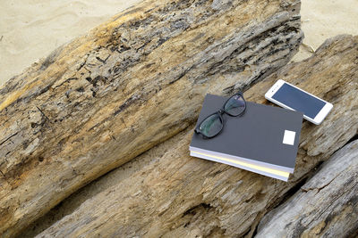 Book with mobile phone and eyeglasses on wood