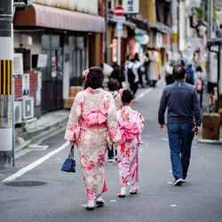 Rear view of people walking on road in city