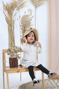 Portrait of cute girl sitting on chair at home