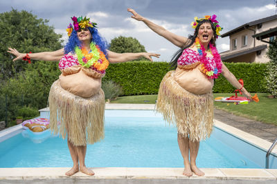 Portrait of women wearing traditional clothing dancing at poolside