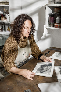 Female artist inspecting some pieces of hand made printings.