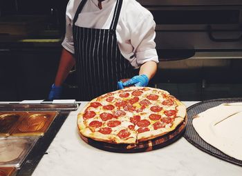 Midsection of man standing in front of pizza