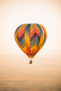 Colorful chevron patterned hot air balloon flying over a hazy nevada desert