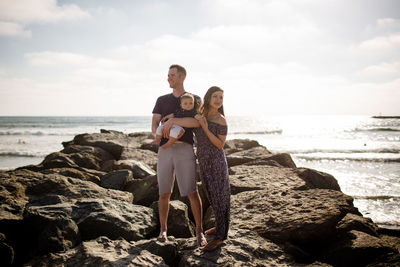 Parents standing on jetty holding infant son