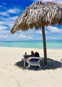 People sitting on chair on beach against sky