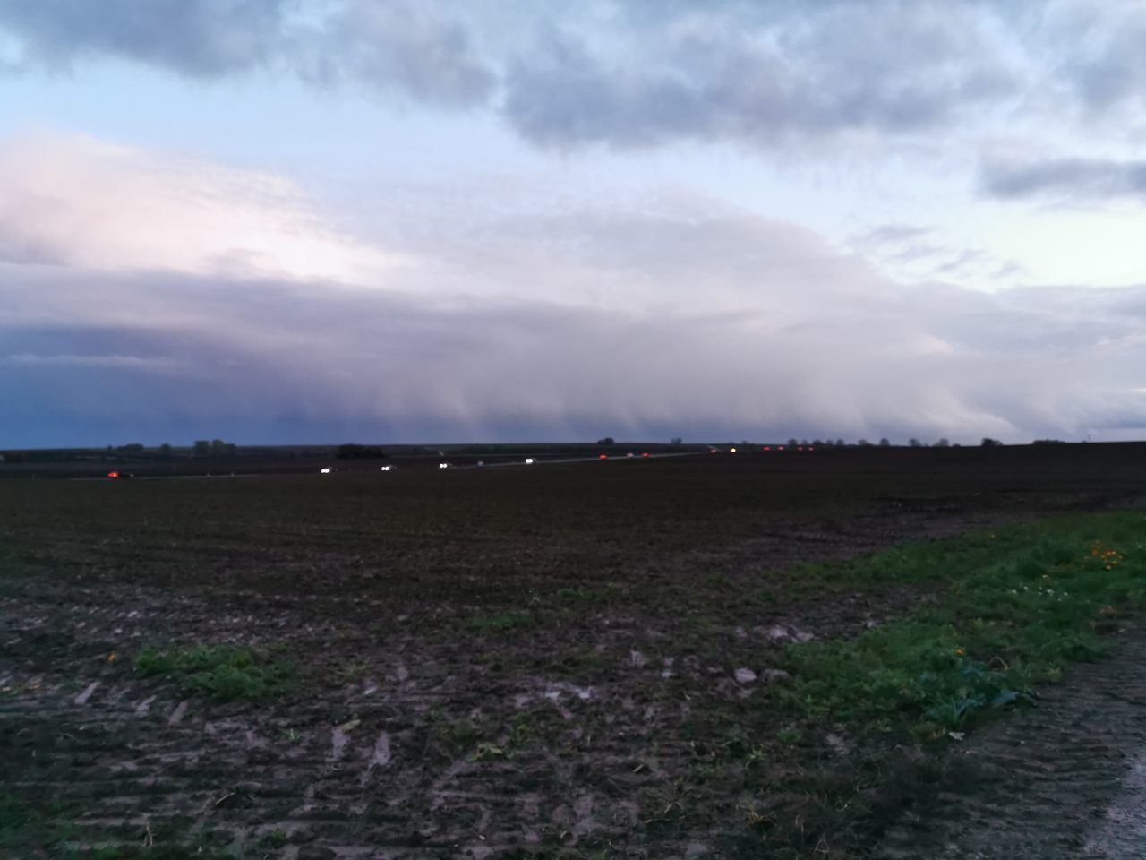 SURFACE LEVEL OF DIRT ROAD AMIDST FIELD AGAINST SKY