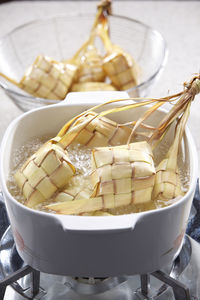 Close-up of ketupats in bowl cooking on stove