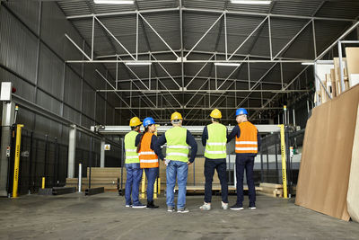 Rear view of workers standing in factory workshop