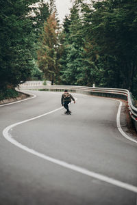 Rear view of boy skateboarding on road