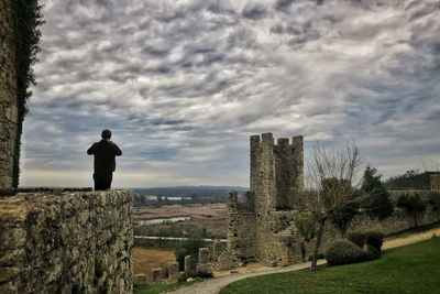 Rear view of man standing on field against sky