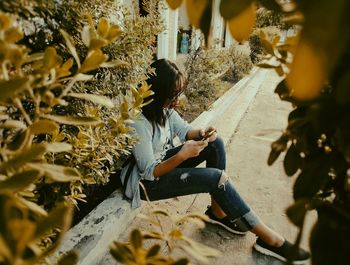 High angle view of woman using smart phone while sitting by plants