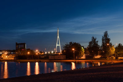 Illuminated bridge over river against sky at night