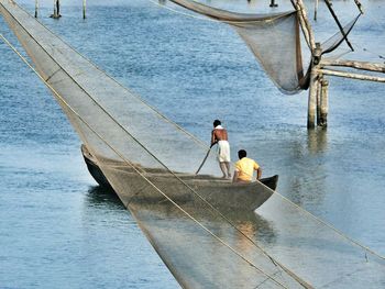 Fishing net against men on boat sailing in river