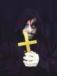 Portrait of spooky priest holding cross