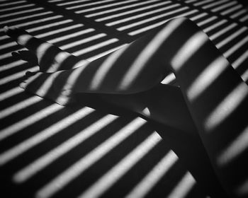 Low section of woman sitting in shadow of blinds