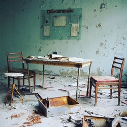 Empty chairs and table in abandoned house