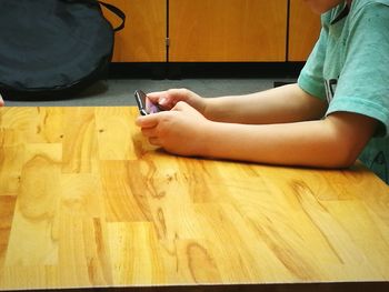 Low section of man using mobile phone on table