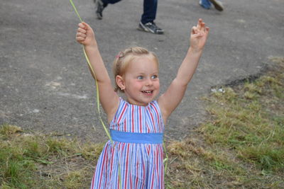 Portrait of happy boy with arms raised in park