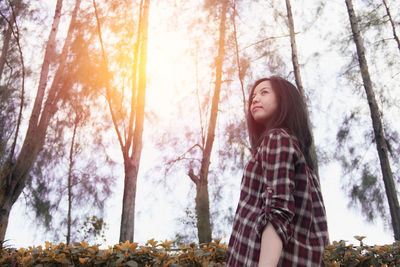 Thoughtful woman looking away against trees