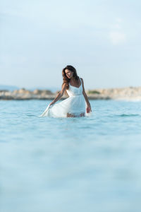 Portrait of young woman in sea against sky