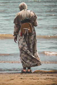 Rear view of woman standing at beach