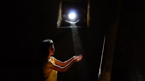 Girl holding illuminated lamp in darkroom