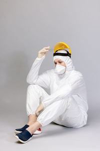 Low angle view of young woman with arms crossed against white background