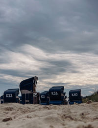 Hooded chairs on beach against sky