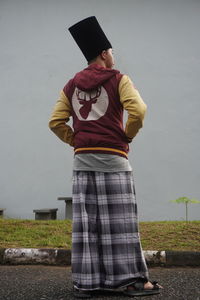 Man wearing hat standing against wall