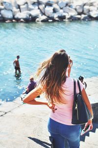 Rear view of woman standing against river