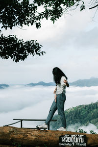 Woman standing by tree against sky