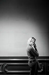 Side view of woman standing against wall