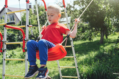 Portrait of boy swinging at playground