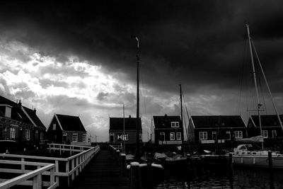 Sailboats moored at harbor against sky