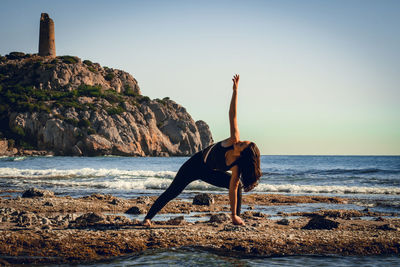 Girl doing yoga on the beach with 3 support points