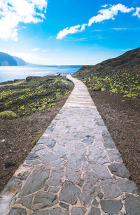 Footpath by sea against sky