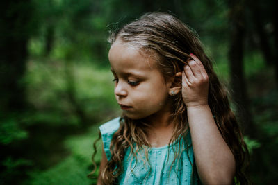 Young biracial girl looking down and fixing hair